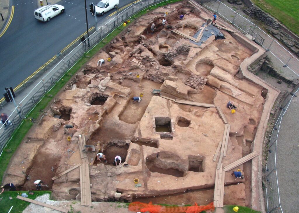An image of an excavation from the air with a portion of the curving walls of the amphitheatre visible